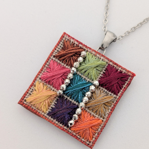 Pendentif couleur vert orange jaune turquoise beige avec des perles blanc